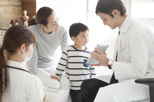The doctor explains it while showing the tablet to parent and child photo