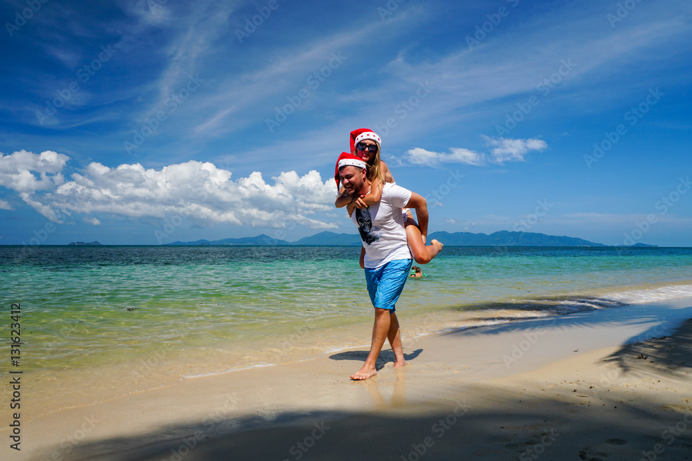 Romantic Couple with Santa Claus Hats Have Fun on the Beach. Celebrating Christmas and New Year in Hot Country Romantic Couple with Santa Claus Hats Have Fun on the Beach. Celebrating Christmas and New Year in Hot Country
