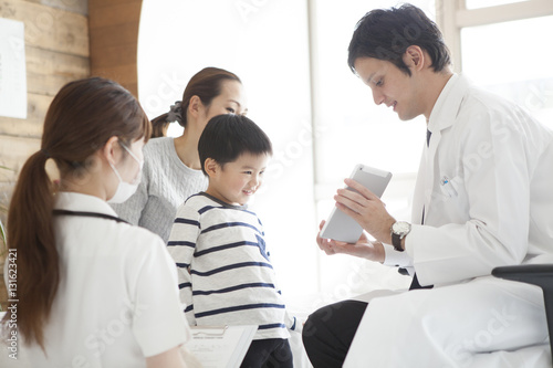 The doctor explains while showing the tablet to the boy