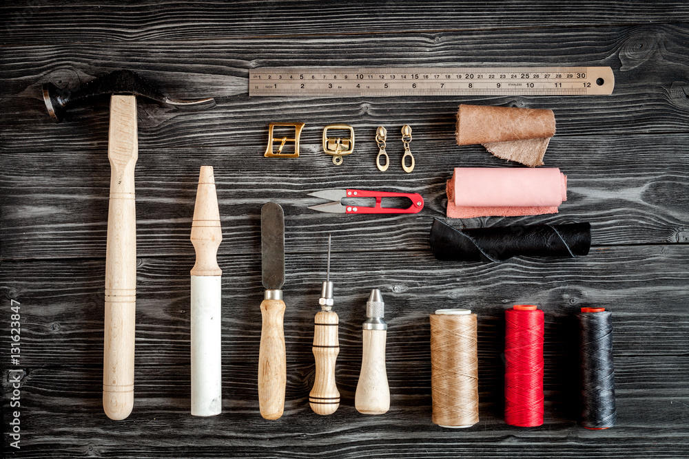 Instruments in leather shop on dark wooden background top view Instruments in leather shop on dark wooden background top view
