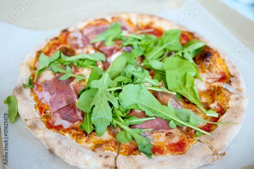 Pizza with parma ham and rockets in takeaway box