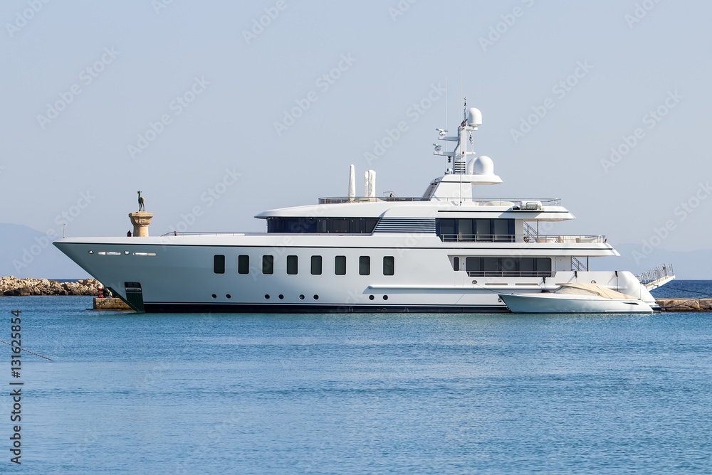 The large modern white private yacht alongside the dock.