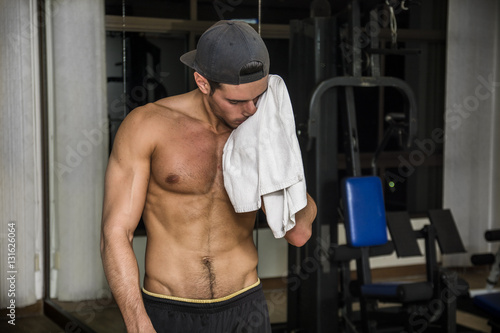 Muscular young man drying sweat with towel