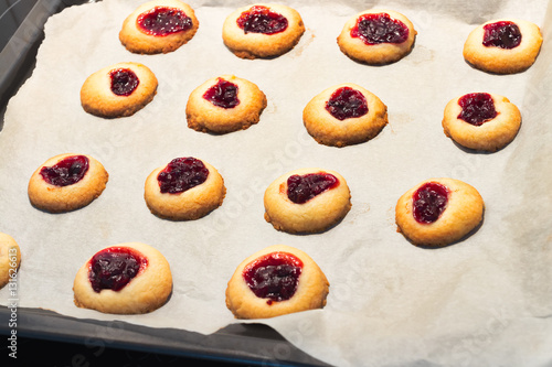 Cookies filled with jelly jam on baking paper.