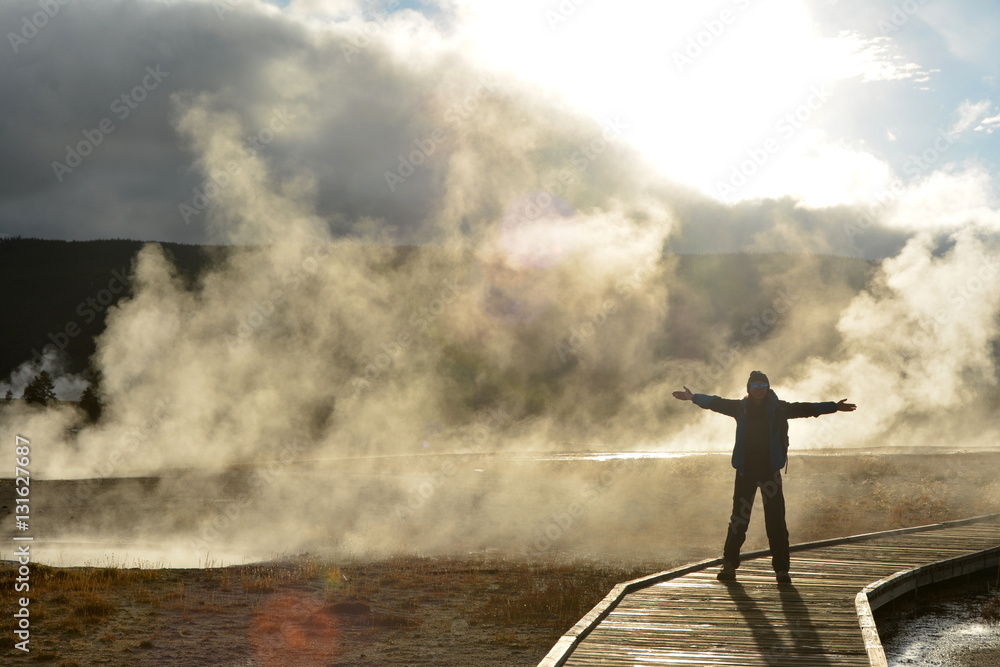 Steam and smoke from the geysers. Silhouette of a girl traveller in Yellowstone national park