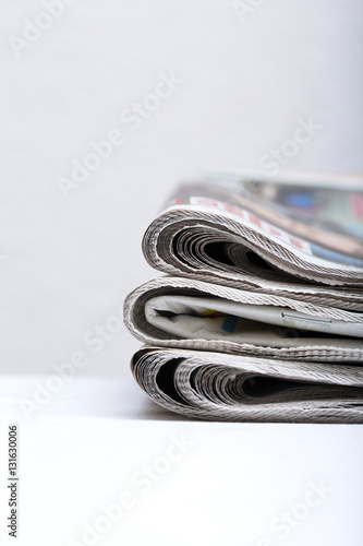 Pile of newspapers on a white table.