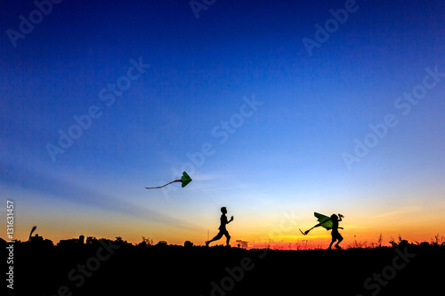 Kid flying a kite in sunset background