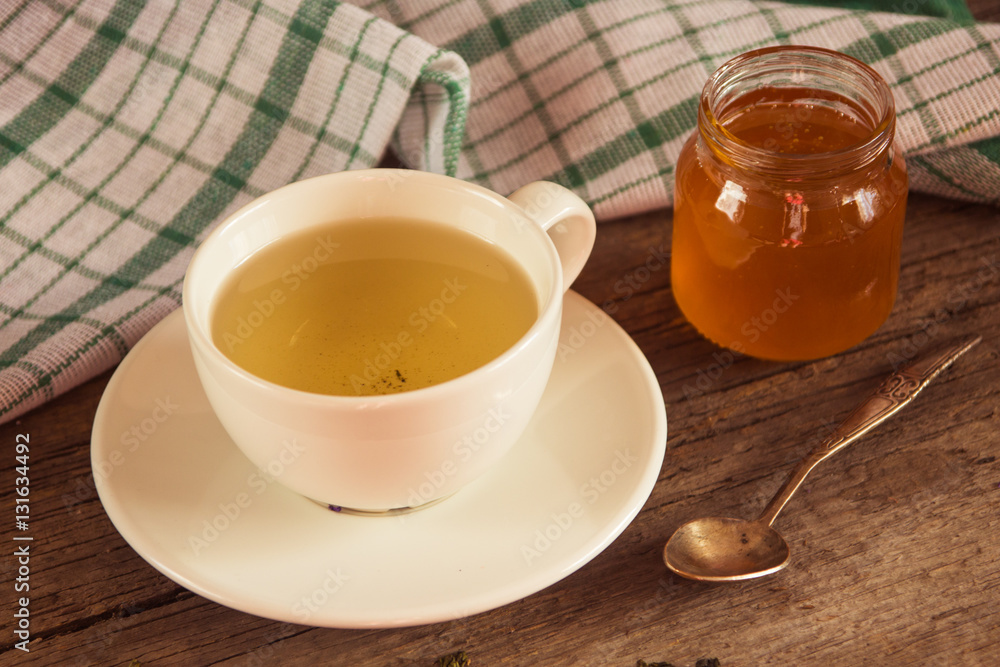 Green tea in a white cup and jar of honey with spoon and green k Green tea in a white cup and jar of honey with spoon and green k