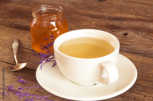 Cup of tea with honey in jar on the wooden table