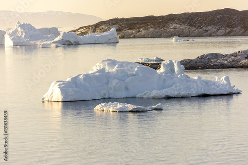 Arctic Icebergs Greenland in the arctic sea. You can easily see that iceberg is over the water surface, and below the water surface. Sometimes unbelievable that 90% of an iceberg is under water photo