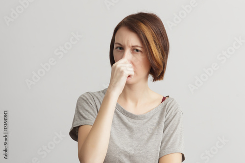 Girl closes her nose because of the odor and stench.