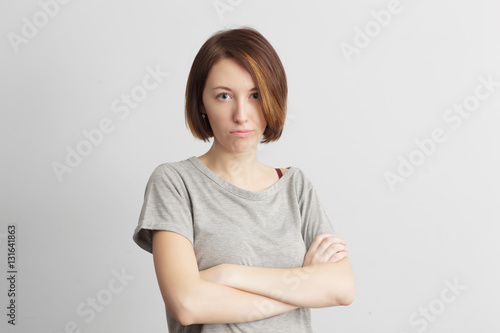 Girl with distrust and doubt looks forward, her arms crossed over her chest.