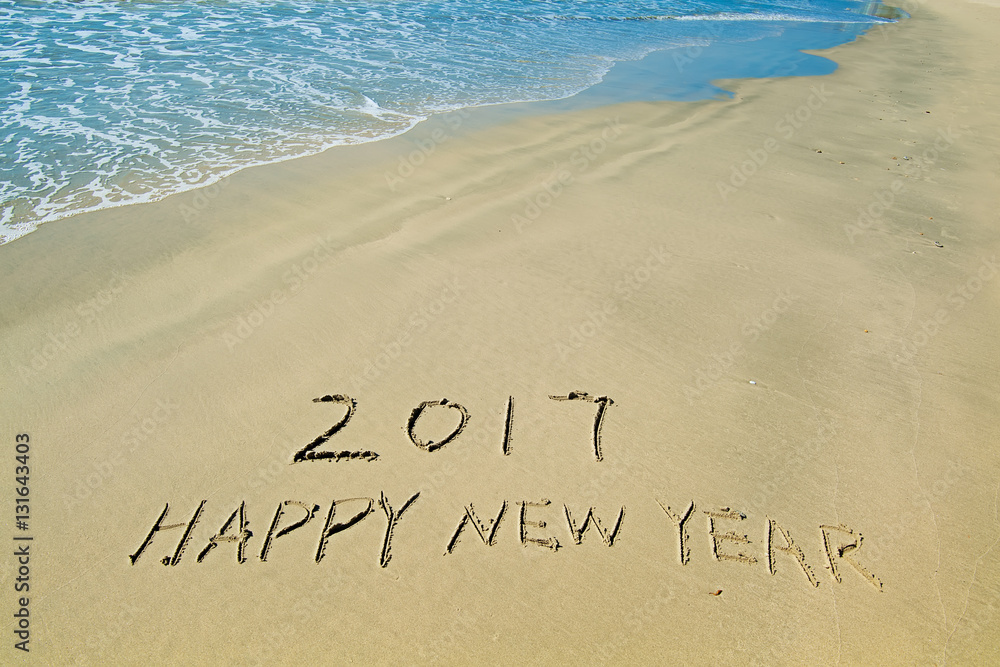 Fototapeta premium 2017 happy new year written in sand write on tropical beach