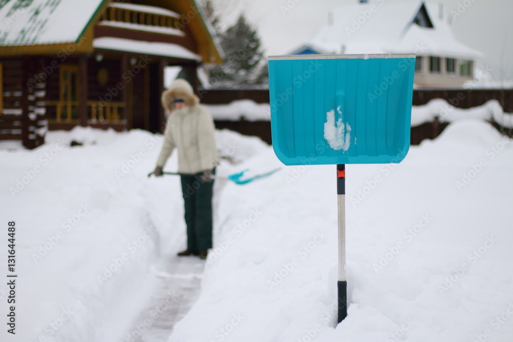 Fototapeta premium Лопата для очистки дорожек от снега стоит в сугробе.