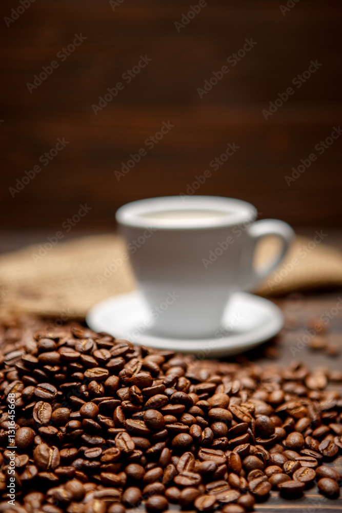roasted coffee beans and cup on wooden background roasted coffee beans and cup on wooden background