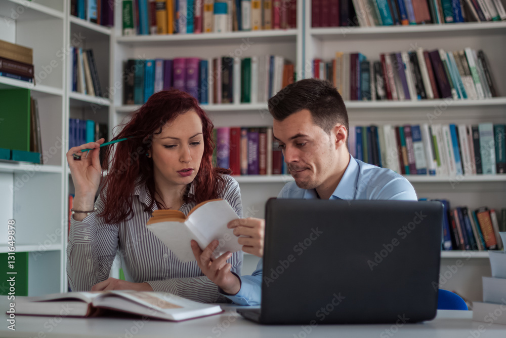 Handsome guy and beautiful redhead girl studying in the library Handsome guy and beautiful redhead girl studying in the library