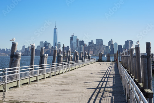 New York city skyline and empty pier with seagulls in a sunny day © andersphoto