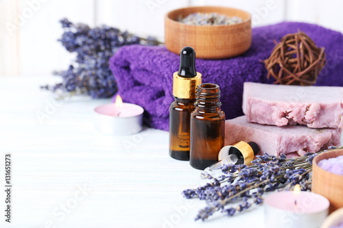 Lavender oil with soap and flowers on white wooden table