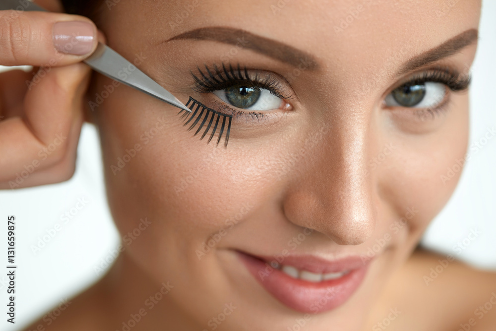 Beautiful Woman Applying Black Long Fake Eyelashes With Tweezers