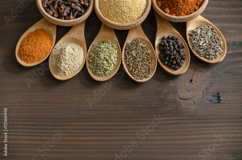 Spices and dried herbs on wooden spoons
