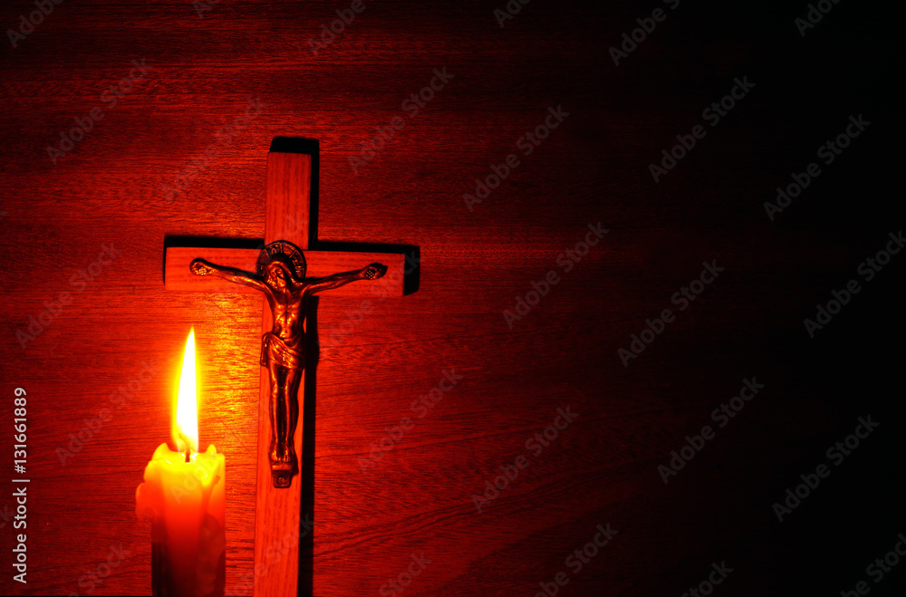 Fire of candle and crucifix in the dark