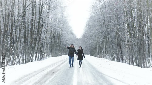 Girl and boy walking along the road into the woods. hold hands. they kiss