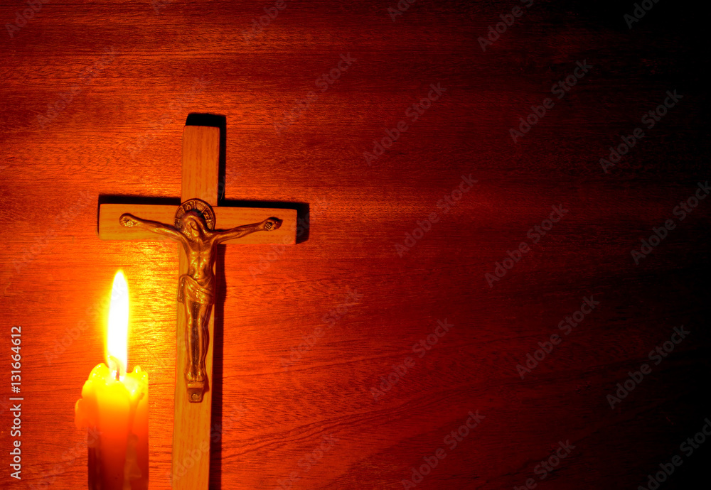 Fire of candle and crucifix in the dark