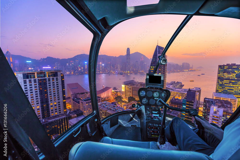 Naklejka premium Kokpit helikoptera latający z lotu ptaka na Port Wiktorii, drapacze chmur i panoramę Hongkongu w nocy.