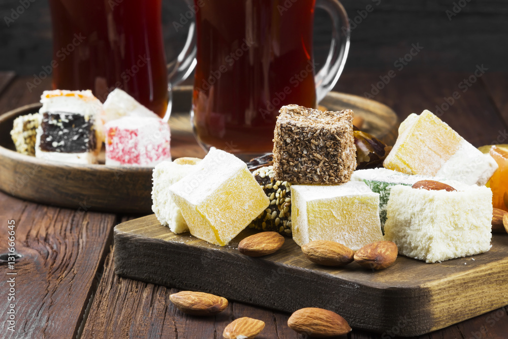 Black tea, oriental sweets, dates and nuts on a dark wooden back