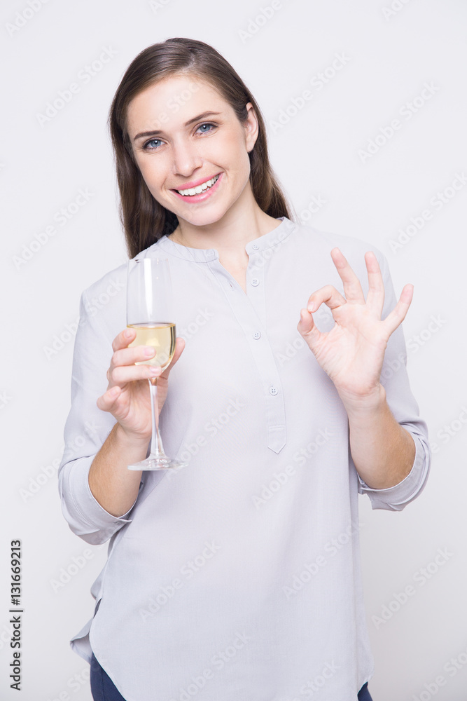 Happy woman holding champagne flute and showing ok Happy woman holding champagne flute and showing ok