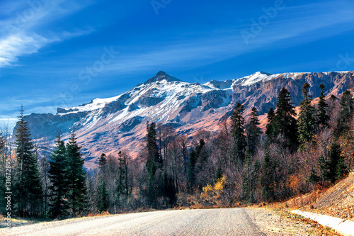Big mountain in autumn with yellow trees and snow-capped mountain view from the road serpentine Caucasus