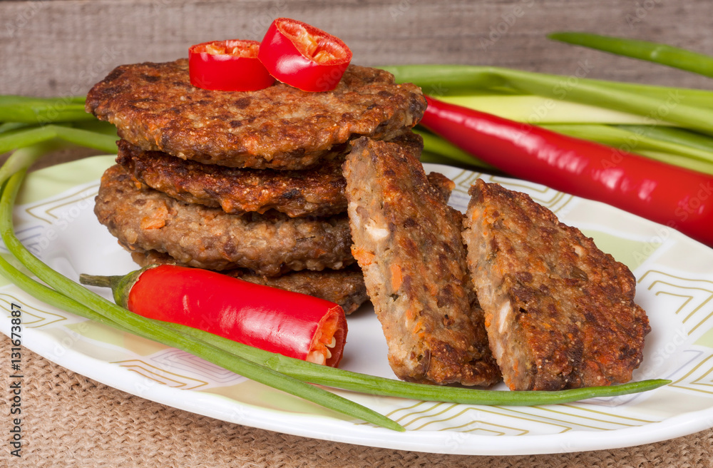 liver pancakes or cutlets with chili pepper and green onions on a wooden background liver pancakes or cutlets with chili pepper and green onions on a wooden background