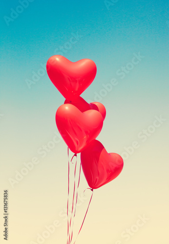 Various red heart shaped balloons in flight