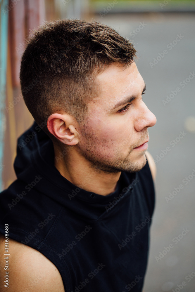 Fototapeta premium Portrait of a strong handsome man in training cloth. Posing in the hood.