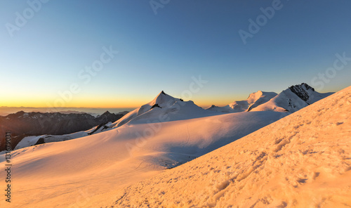 XXL panorama of sunrise at 3800m amsl in the Swiss Wallis Alps near the summit of Alphubel  4206m .Allalinhorn  Strahlhorn   Rimpfischhorn in the background  left to right .Snow fields in foreground.