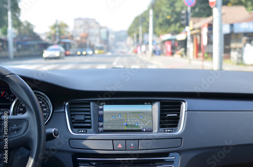 View from inside a car on a part of dashboard with a navigation unit and blurred street in front of a car © branislav
