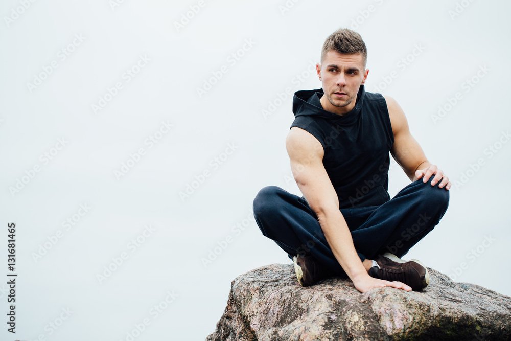 Strong fitness yoga man in lotus pose on the rock beach near the ocean. Harmonic concept. Strong fitness yoga man in lotus pose on the rock beach near the ocean. Harmonic concept.