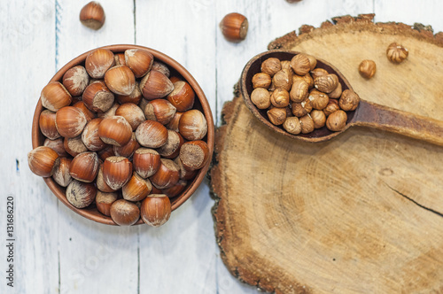 Hazelnuts in a bowl near a spoon peeled walnut on a wooden surfa photo