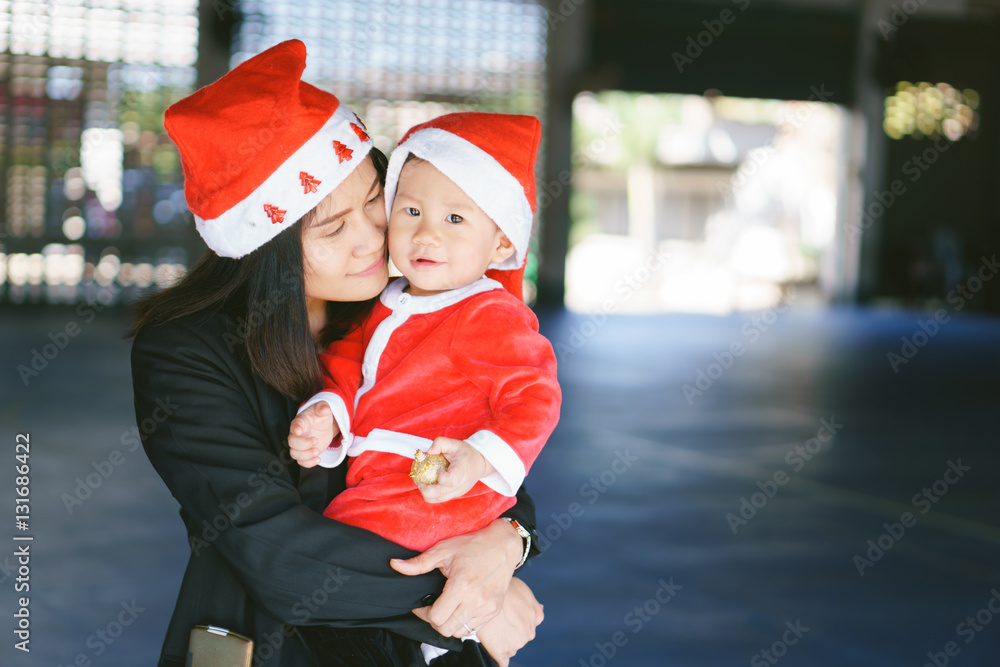 Obraz premium Asian mother holding baby in santa suit