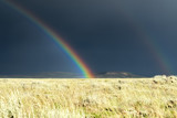 The Rain stays Mainly on the High Plians - A rainbow on the high mountain plains just as the storm passes over with the sun full behind the photographer.