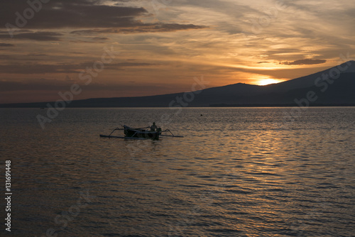 Sunset with fisher man fishing in a boat in ocean near Gili Air