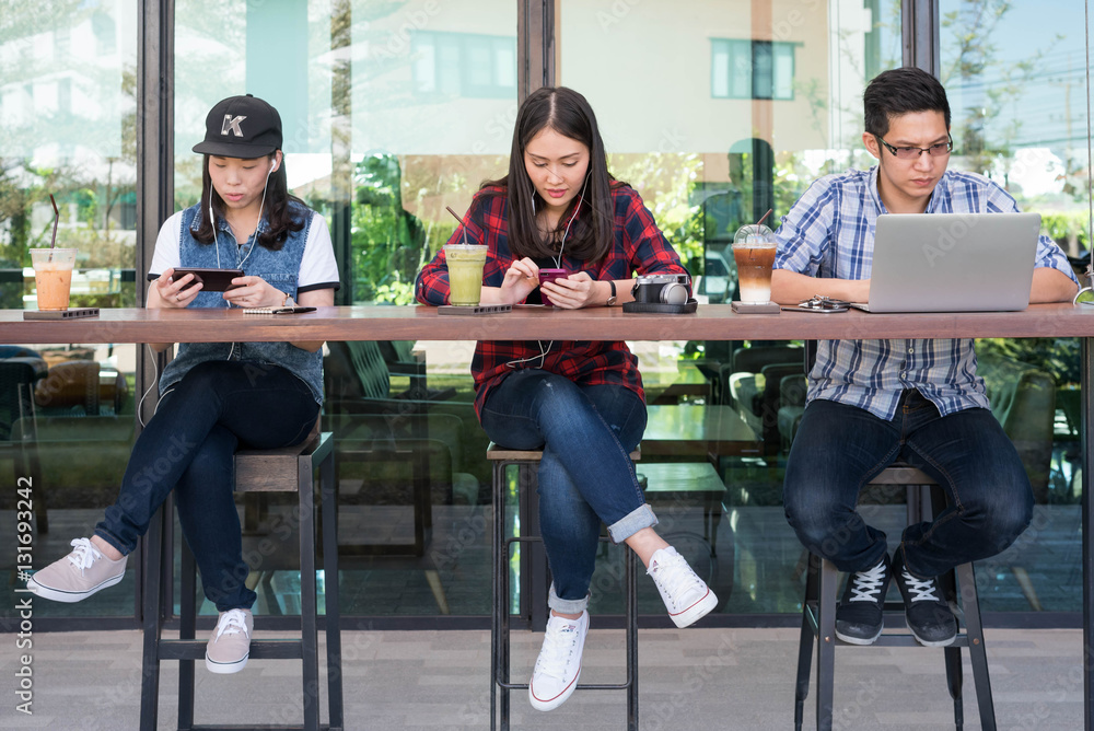 three people using smartphone, tablet, and laptop in coffee shop three people using smartphone, tablet, and laptop in coffee shop