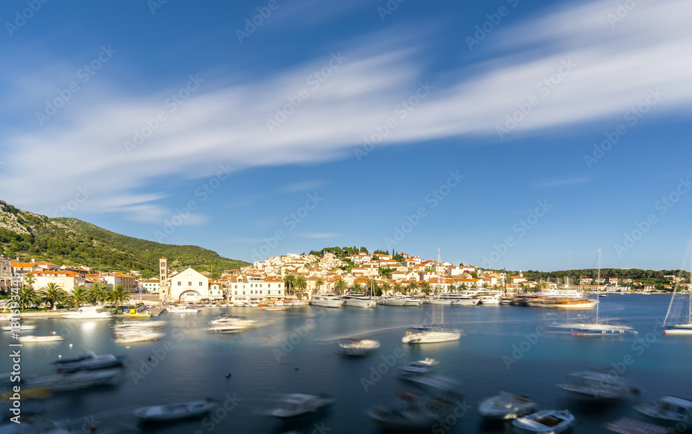 The blurred movement of boats shows the busy port in Hvar Town in Croatia in summer, a popular travel destination in Europe.