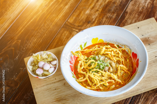 Curried noodle soup (Khao soi) with chicken meat and spicy coconut milk in sunlight. Thai food.