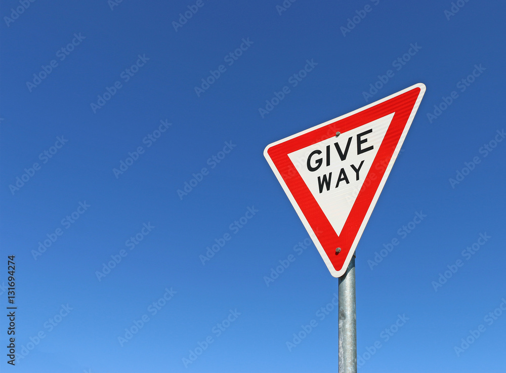 red, black and white give way road sign in a bright blue sky red, black and white give way road sign in a bright blue sky