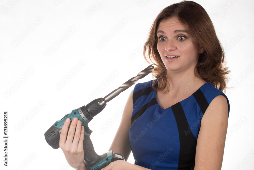 Girl with a working tool screwdriver laughing on a white backgro Girl with a working tool screwdriver laughing on a white backgro