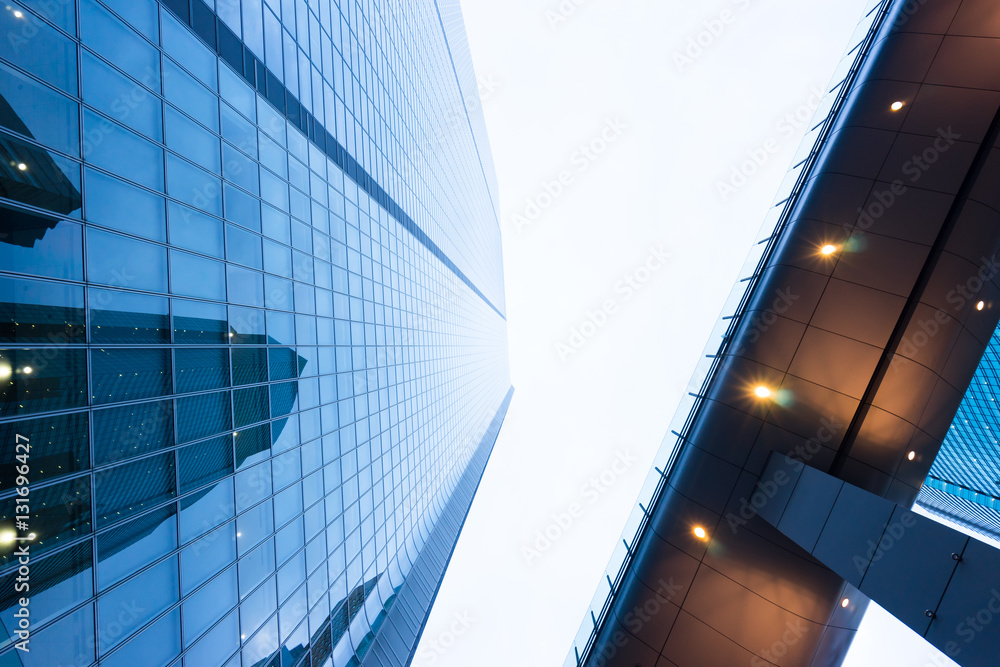 Obraz premium Business concept for real estate and corporate construction - looking up view in financial district, the silhouettes of skyscrapers city reflect dramatic blue sky, sun lights in Tokyo, Japan