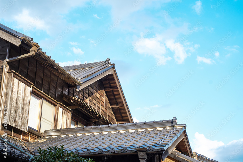 Asia culture concept - japanese traditional historical wooden old house under golden sun and morning blue cloudy sky in Japan Asia culture concept - japanese traditional historical wooden old house under golden sun and morning blue cloudy sky in Japan