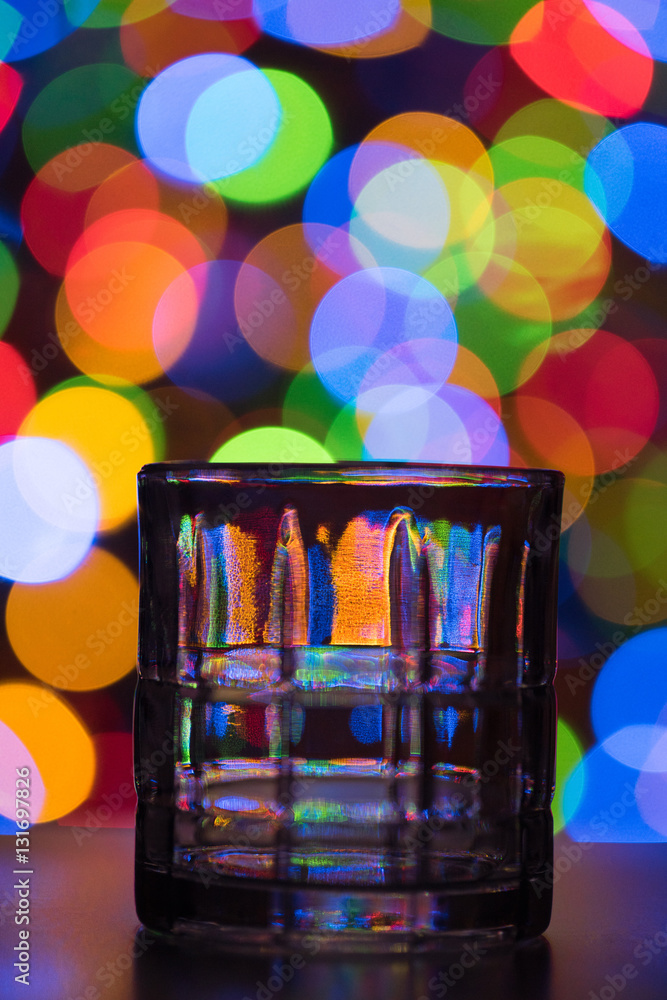 Tumbler glass on dark, multi-colored bokeh background Tumbler glass on dark, multi-colored bokeh background