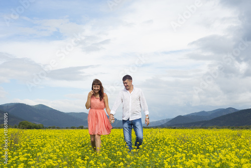 Lovers man and woman walk on the flower field.